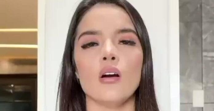 A young woman with long dark hair and subtle makeup displays a confident expression in a well-lit interior setting.$# CAPTION