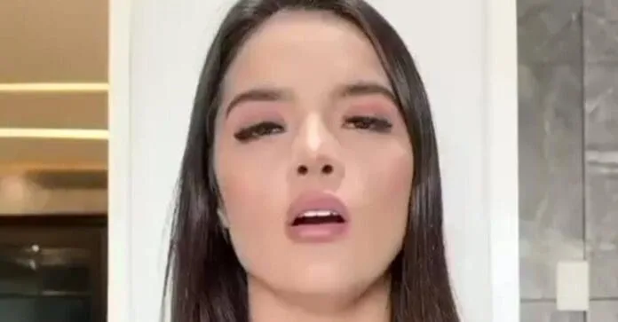 A young woman with long dark hair and subtle makeup displays a confident expression in a well-lit interior setting.$# CAPTION