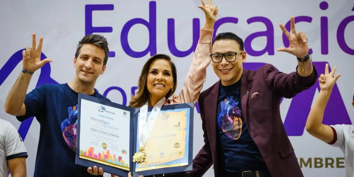 Three individuals holding a certificate and posing for a photo at an education event, with the background featuring the word "Educación."