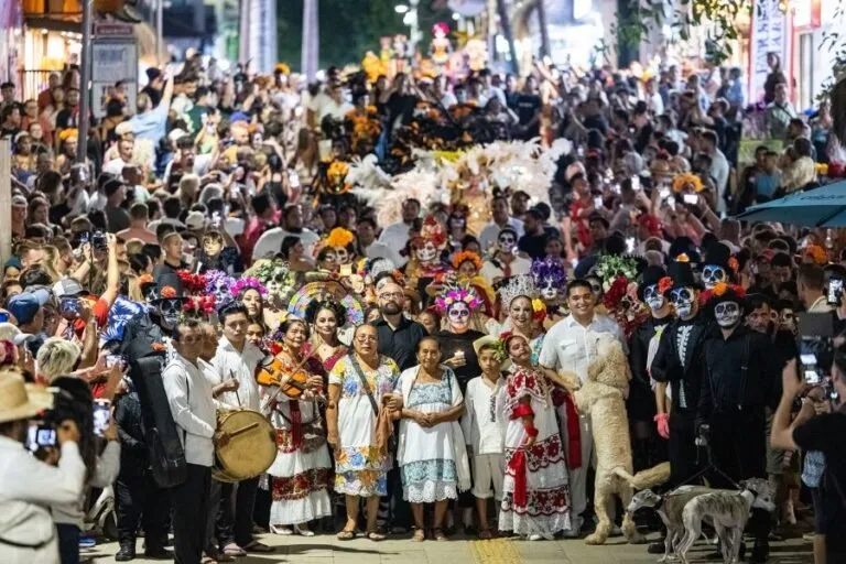 A vibrant crowd in traditional attire celebrating a cultural event, with people in colorful costumes and face paint, surrounded by onlookers.$#$ CAPTION