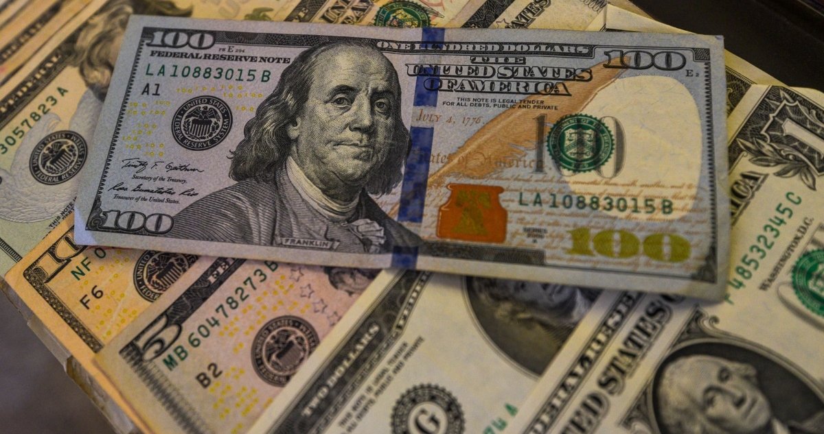 A close-up view of a one hundred dollar bill featuring Benjamin Franklin, surrounded by various denominations of U.S. currency.
