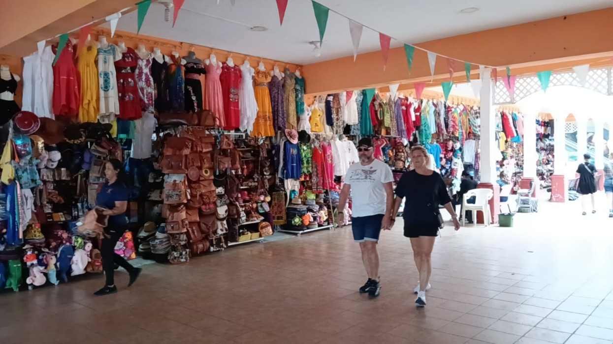 A colorful market featuring clothing and bags with two people walking hand in hand in the foreground.$#$ CAPTION