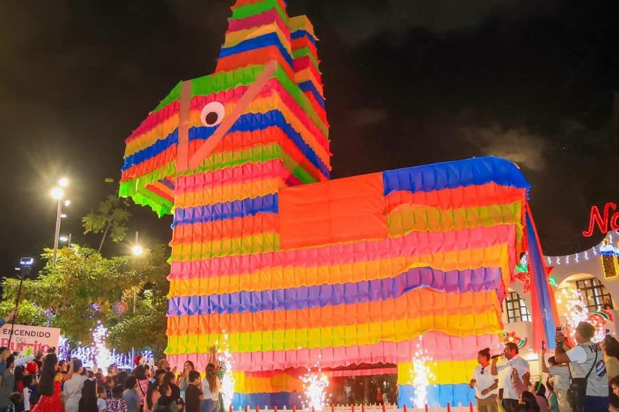 a large brightly colored piñata in the shape of a donkey surrounded by people celebrating at night