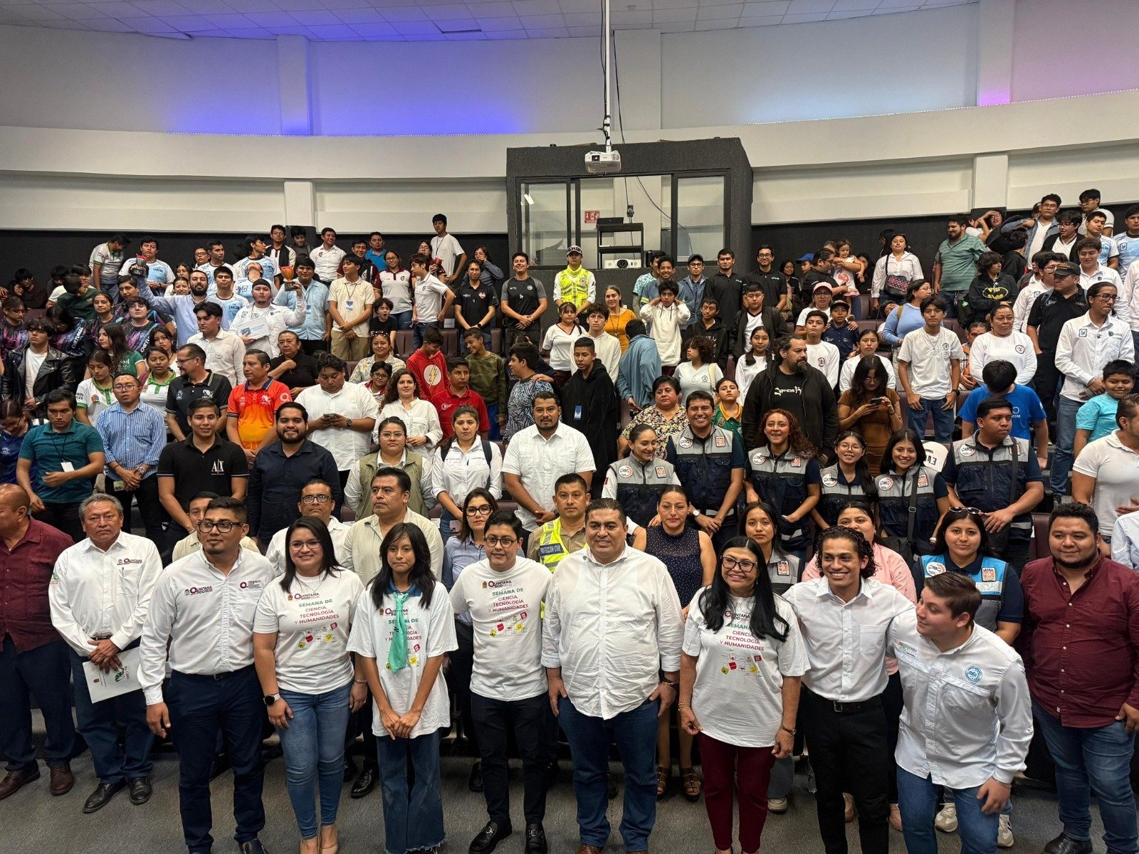 A large group of people, including attendees and organizers, pose for a photo at an educational event, showcasing a diverse crowd in a conference setting.$# CAPTION