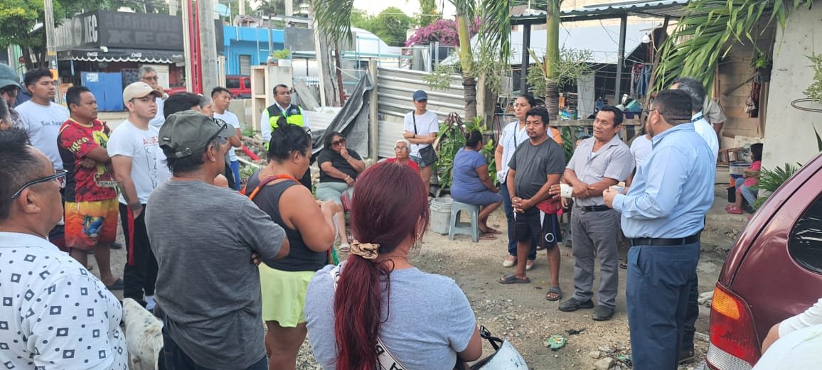 A group of people gathered outdoors for a community meeting, discussing local issues in a neighborhood setting.$# CAPTION