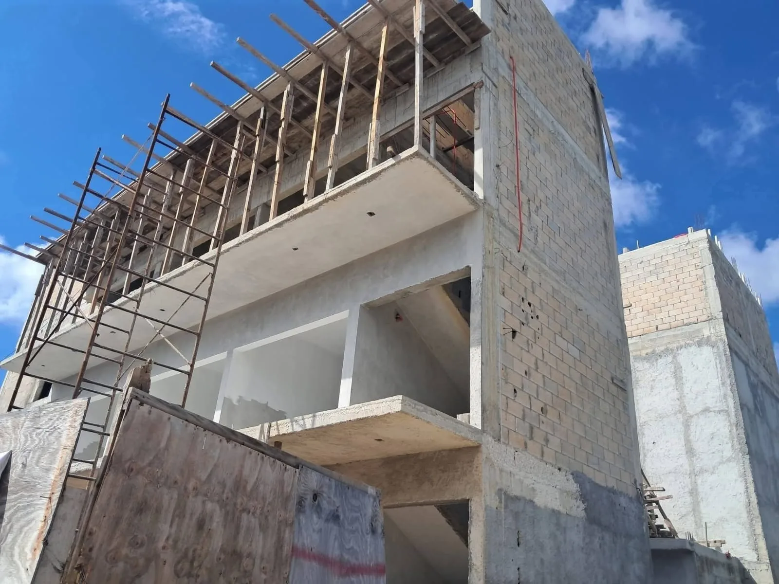 A partially constructed building with scaffolding, exposed walls, and a clear blue sky in the background.$#$ CAPTION