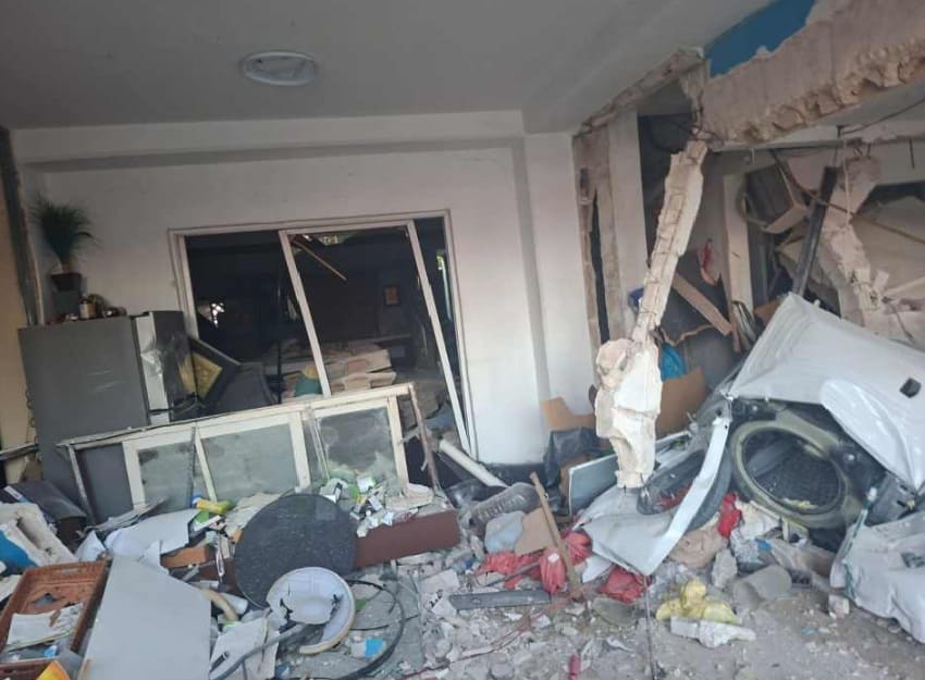 A room heavily damaged with debris scattered everywhere, showing signs of destruction.