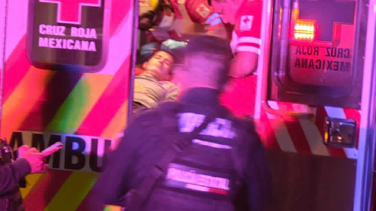 A scene showing emergency medical personnel attending to a patient inside an ambulance, with a police officer present outside the vehicle.$#$ CAPTION