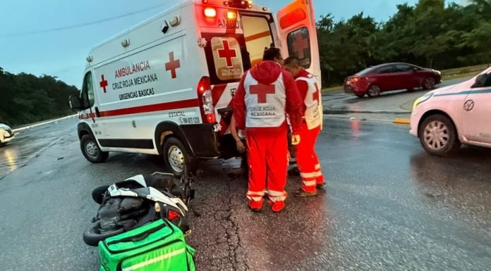 Paramedics unloading equipment from an ambulance on a rainy road
