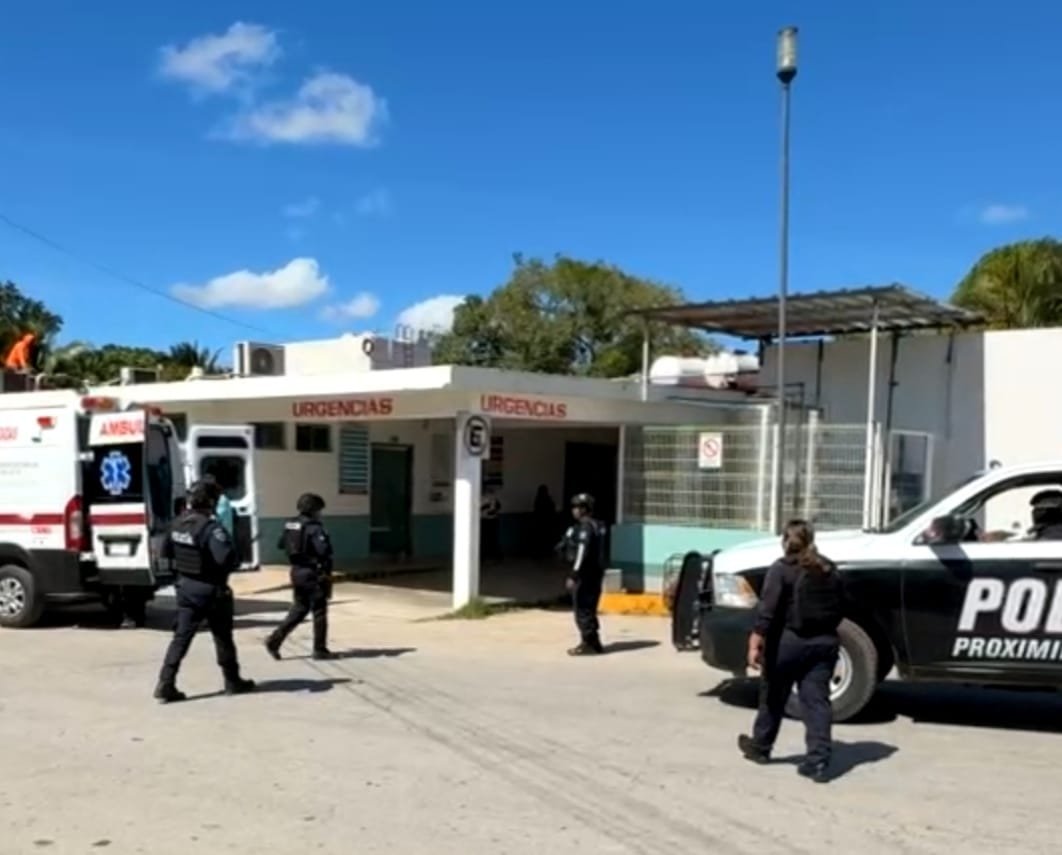 A group of police officers and an ambulance are present outside an emergency medical facility. The building is labeled "URGENTCIAS."