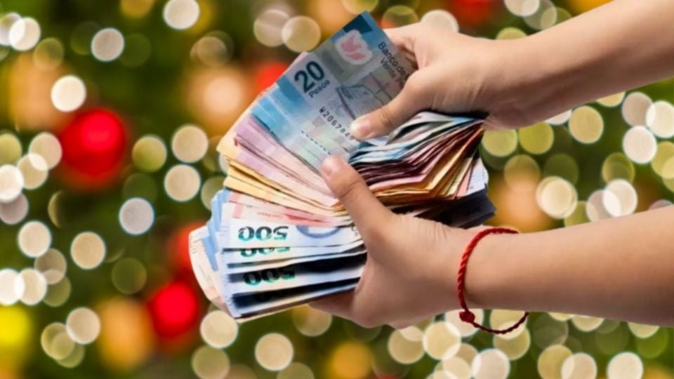hands holding a fan of colorful banknotes in front of a blurred festive background