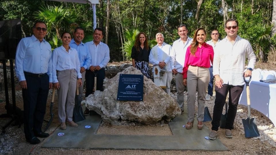 Group of people gathered around a ceremonial stone at a groundbreaking event in a natural setting
