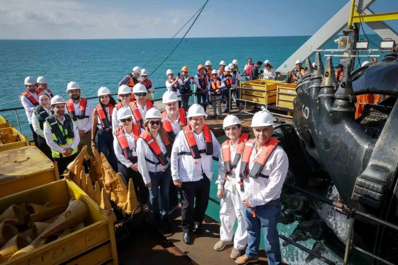 a group of people in safety gear standing on a ship near the ocean