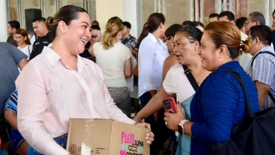 a woman smiling while holding a box engages with others in a crowd-14112025