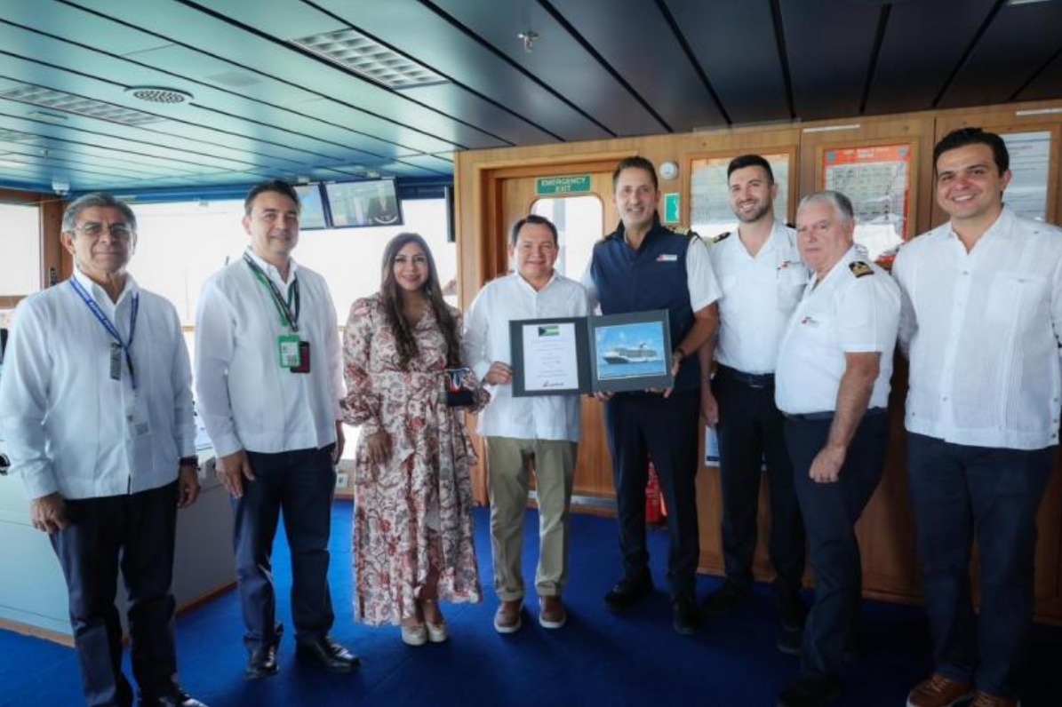 A group of people in formal attire, standing together inside a ship's control room, holding a certificate and posing for a photo.$# CAPTION
