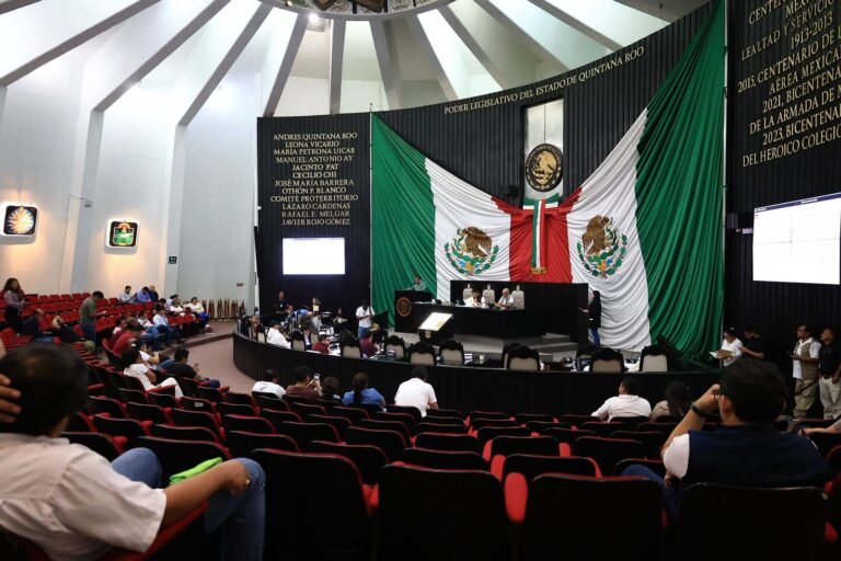 A view of the legislative chamber in Quintana Roo, Mexico, featuring the national flag and seated members in a formal discussion setting.$# CAPTION