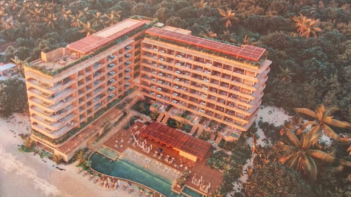 aerial view of a modern hotel near a beach surrounded by palm trees