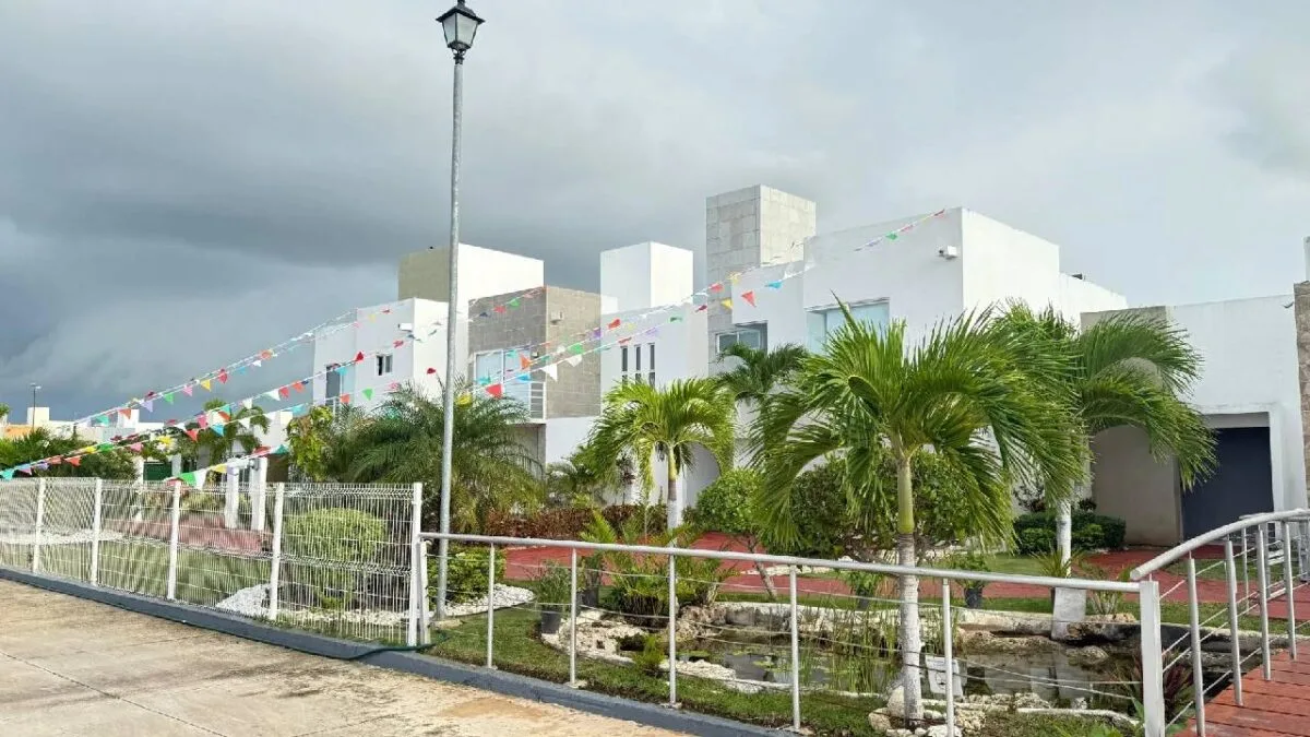 a modern house surrounded by palm trees with colorful flags hanging across the entrance-26112025