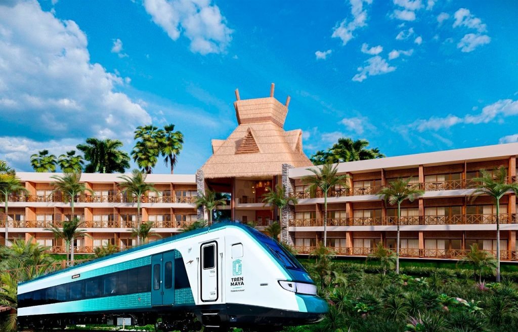 A sleek train in front of a modern hotel building with palm trees and blue skies in the background.