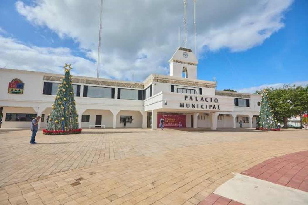 A view of the Municipal Palace with a decorated Christmas tree in front on a sunny day.$# CAPTION