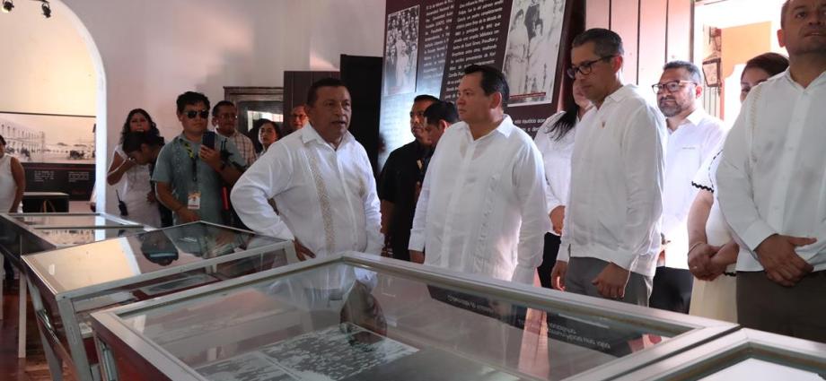 Local leaders touring a museum exhibit with glass displays and informational panels in the background.$# CAPTION