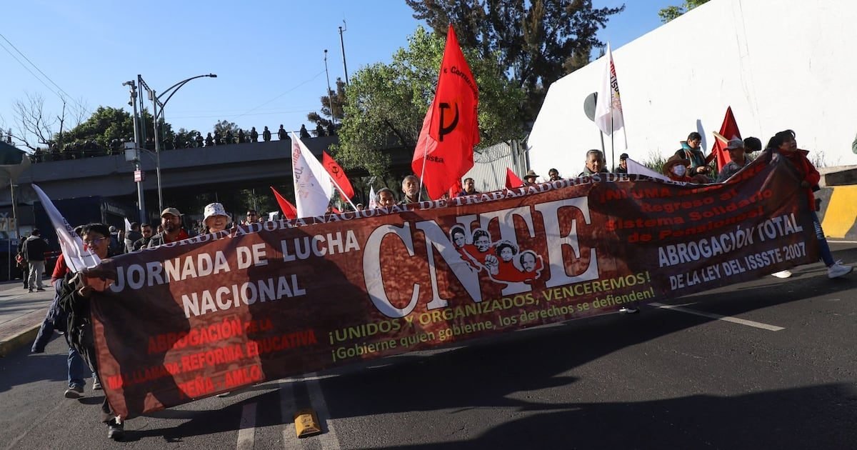 A large group of protesters holding a banner and flags during a national demonstration in Mexico, advocating for labor rights and education reform.$# CAPTION