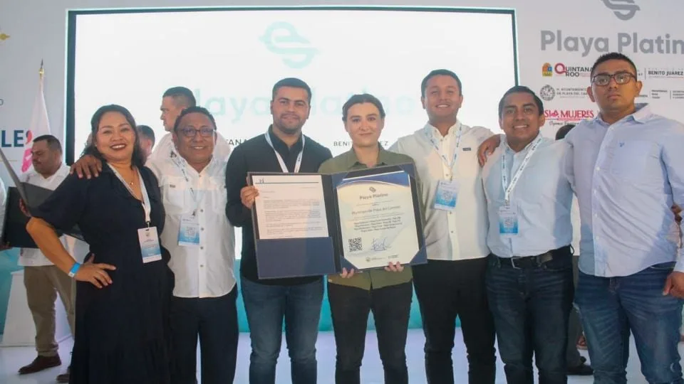 Group of people at a ceremony holding a certificate with a large screen in the background displaying Playa Platinum logo