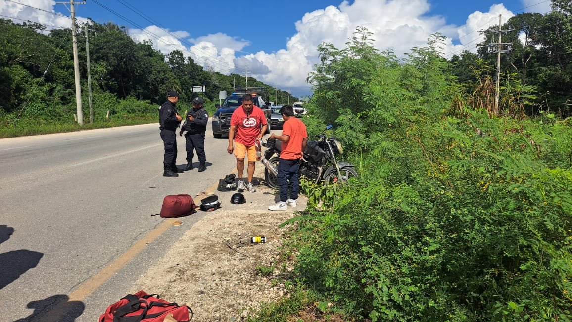 police and individuals interacting beside a motorcycle on a roadside surrounded by greenery
