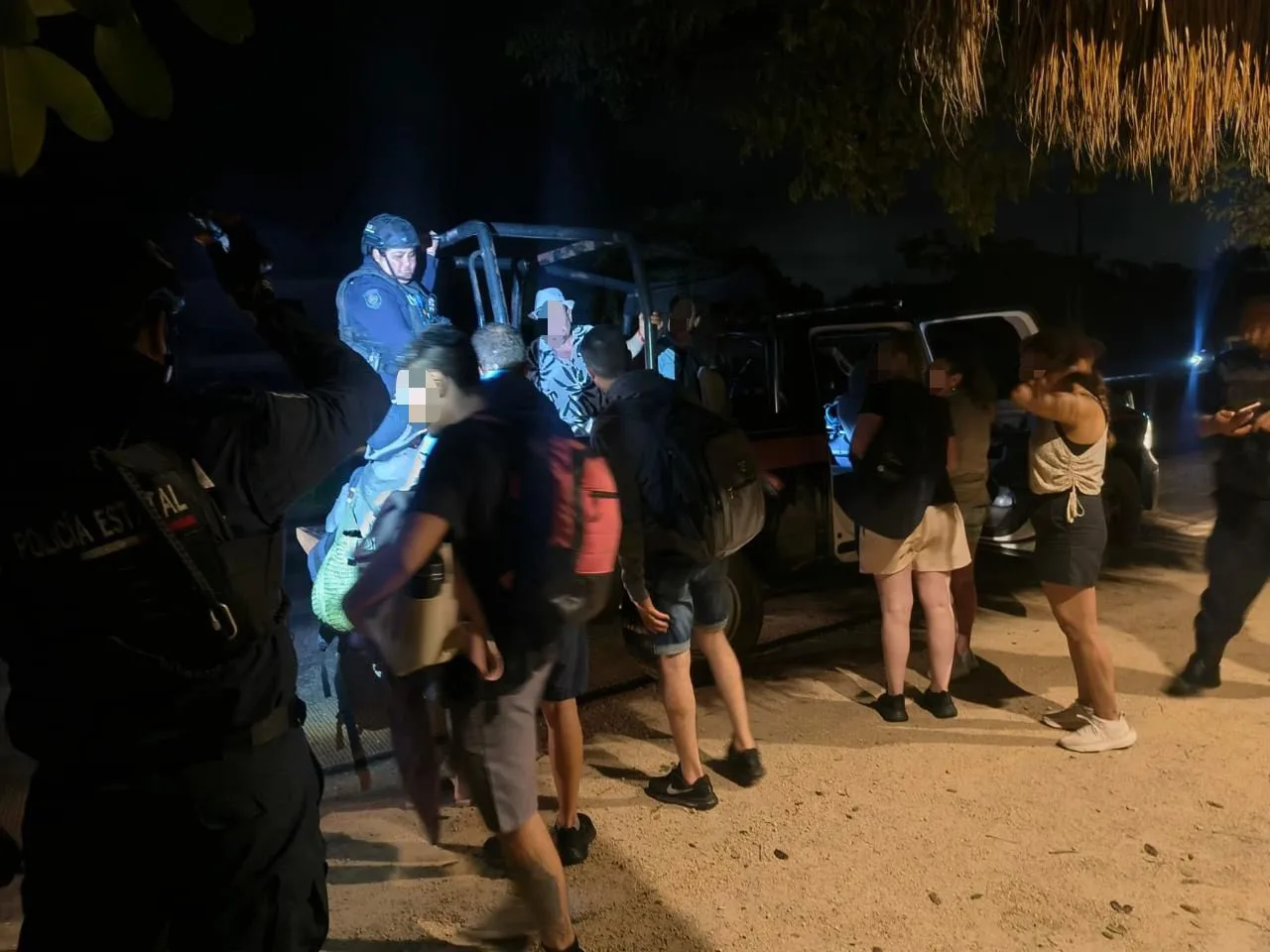 Law enforcement officers interacting with a group of individuals at night under artificial lighting.