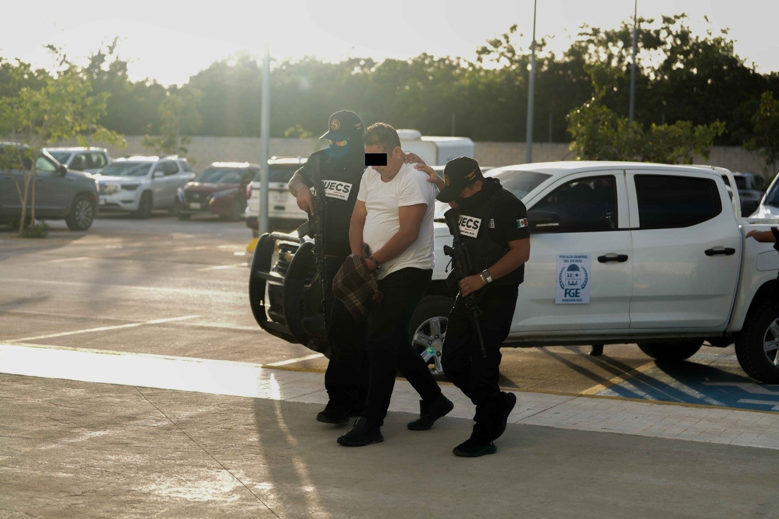 two armed officers escorting a detained individual in a parking lot-06112025