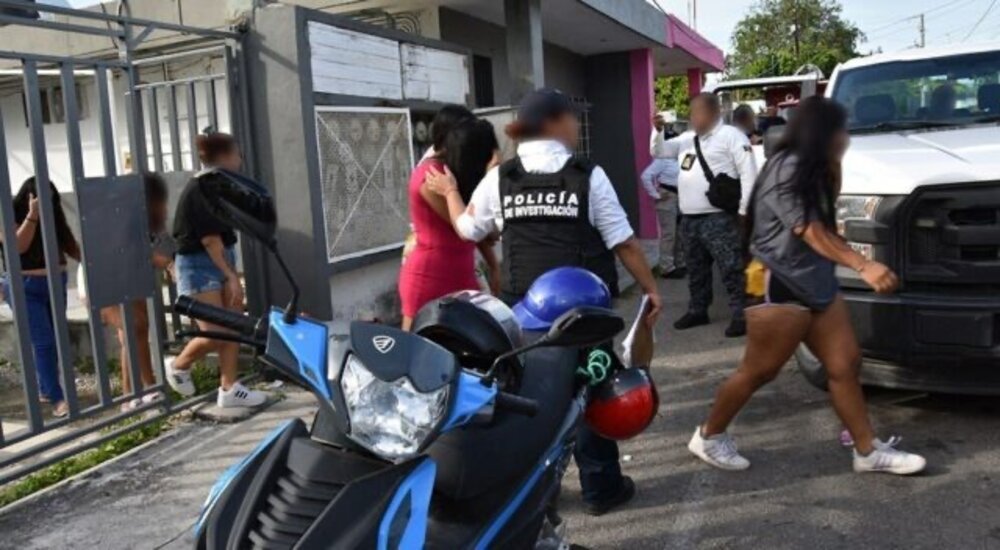 Law enforcement officers interacting with individuals outside a building, with a motorcycle parked nearby.$#$ CAPTION