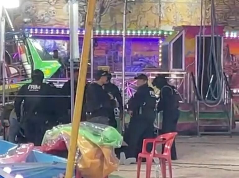 A group of law enforcement officers gathered at a fairground with colorful attractions in the background. There are various carnival rides and decorations visible.$#$ CAPTION