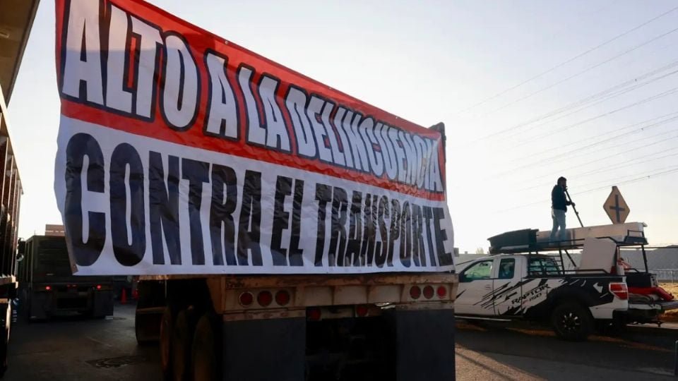 a large banner reading alto a la delincuencia contra el transporte is displayed in a protest setting with vehicles in the background