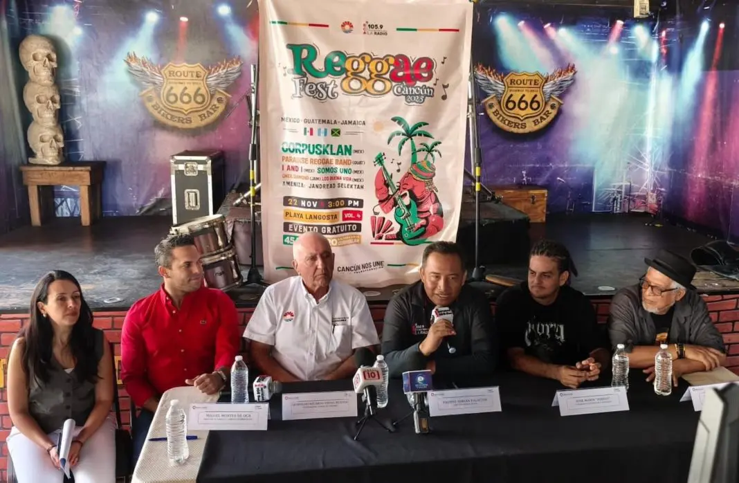 A group of speakers at a press conference for Reggae Fest Cancun 2023, with a colorful event banner in the background.