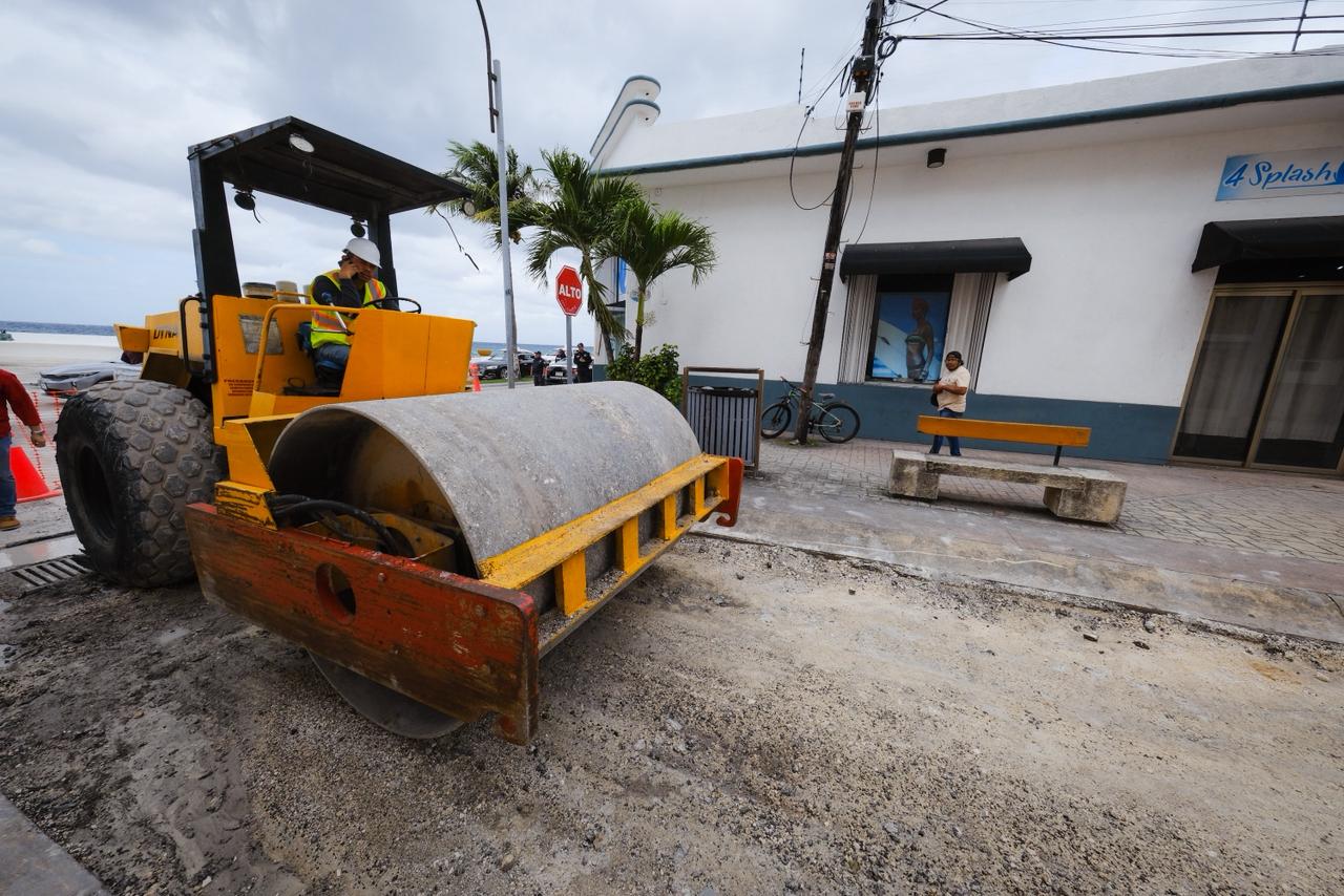 A construction vehicle working on a road near the beach with a cloudy sky in the background.$# CAPTION