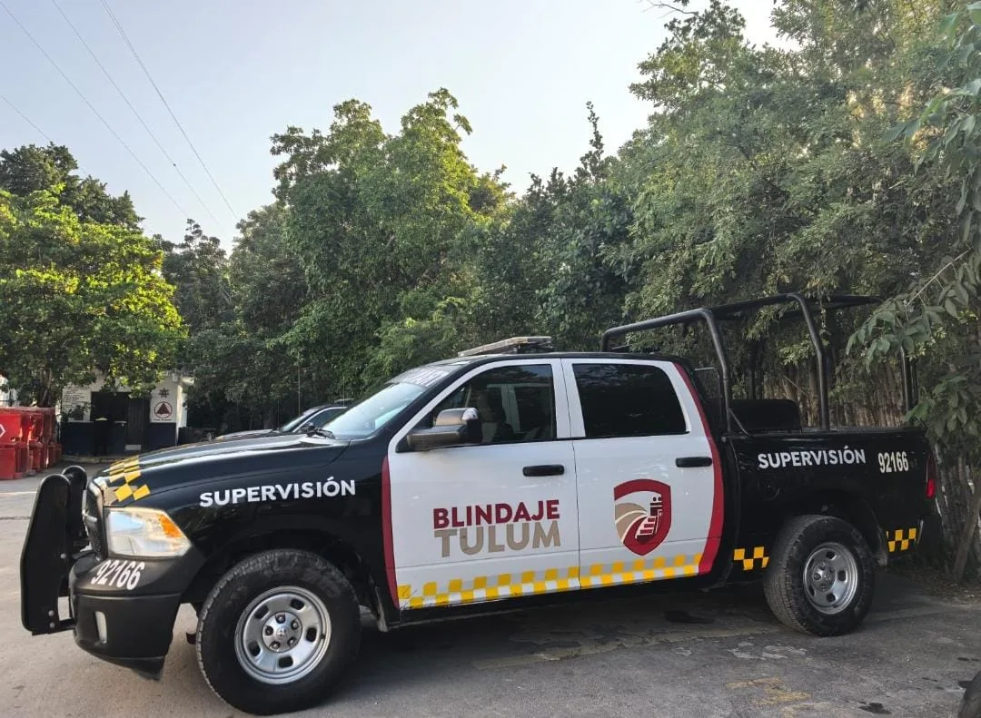A security truck with a black and white design parked among greenery in Tulum, Mexico.$# CAPTION