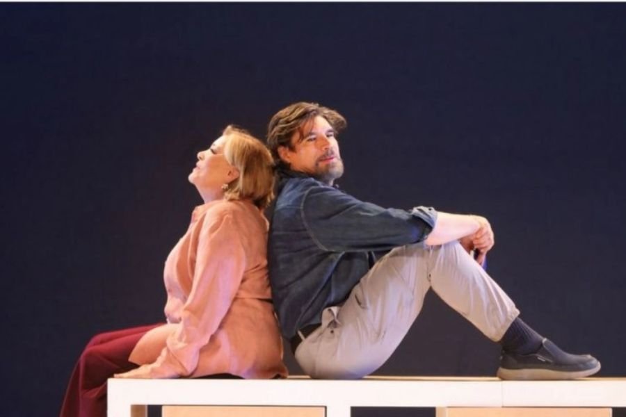 two actors seated back to back on a stage-21112025