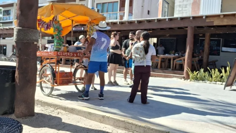 a street vendor cart selling elotes with customers nearby-22112025