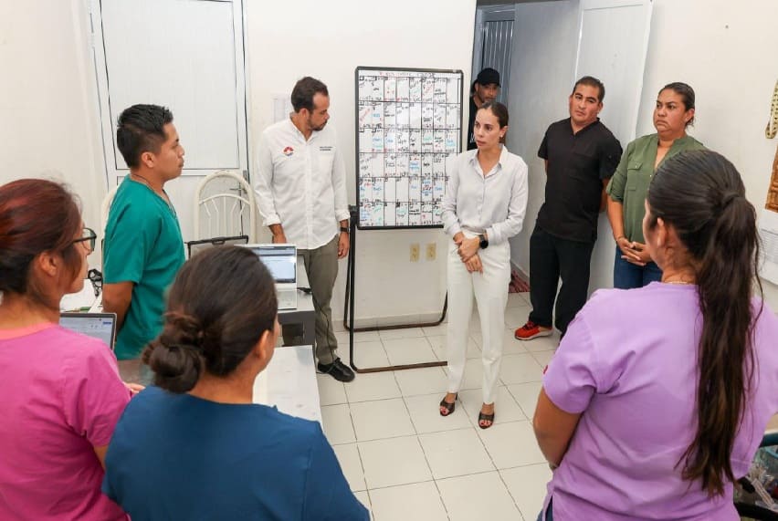 A group of healthcare professionals gathered in a meeting room, discussing plans with a calendar in the background.$# CAPTION