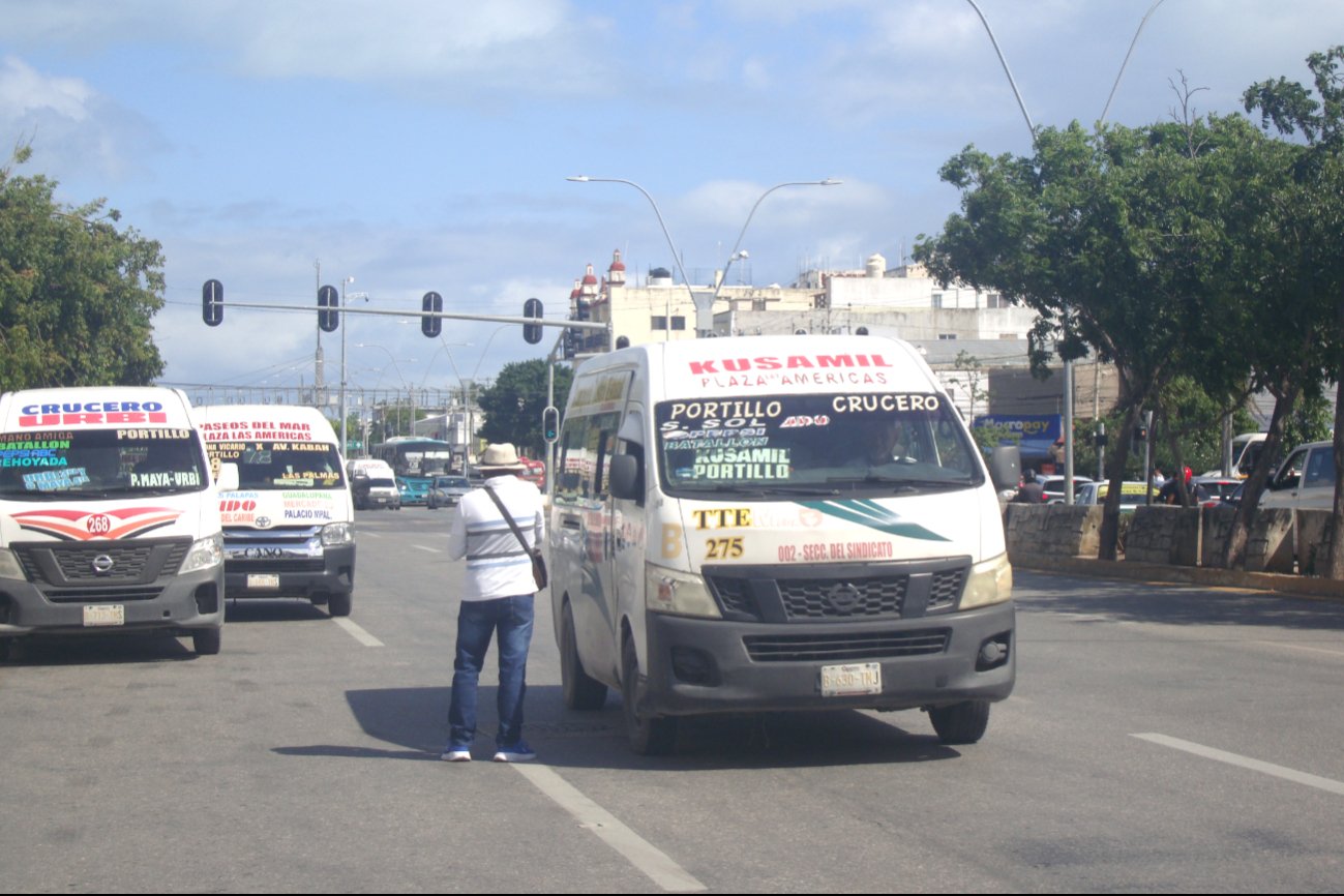A street view showing several vans, including a Kusamil van, stopped at a traffic signal in a busy area.$# CAPTION