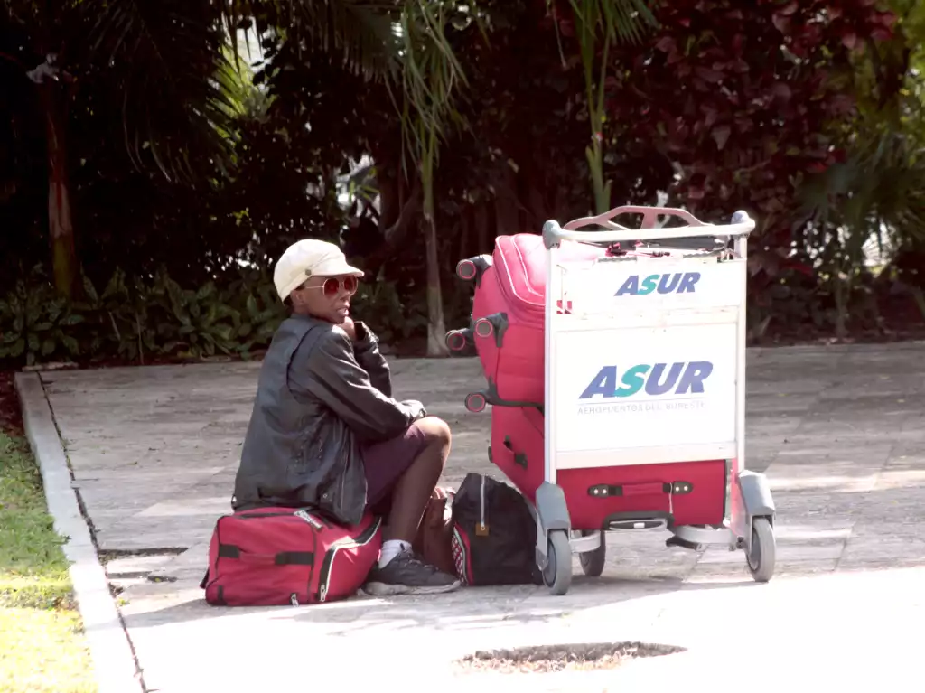A traveler takes a moment to rest while waiting at the airport with their luggage nearby.