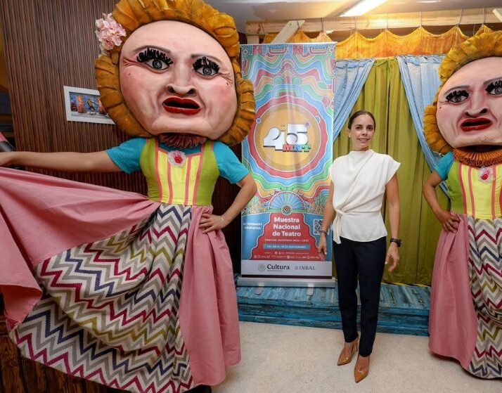 a woman stands between two performers in large, colorful puppet costumes at a theatrical event in quintana roo