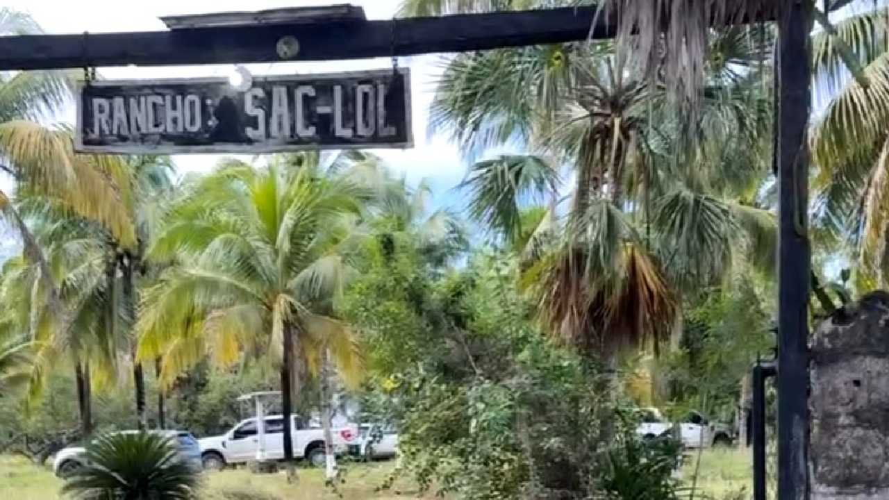 A sign reading "Rancho Sac-Lol" surrounded by palm trees and greenery