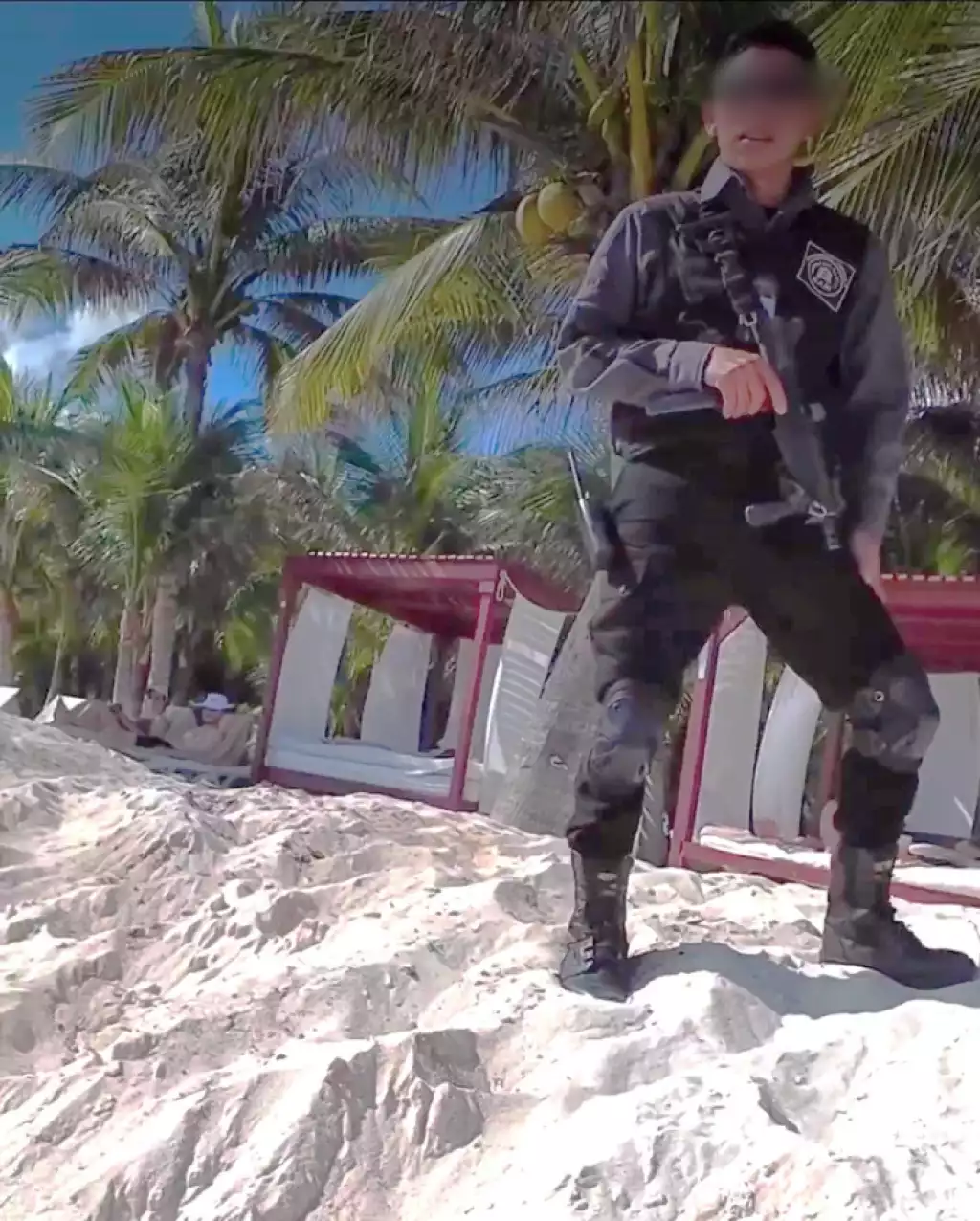 Video screenshot showing an armed guard patrolling the beach in front of Dorado Seaside hotel in Riviera Maya