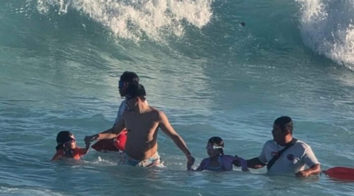 Lifeguards rescuing two minors from the water on a Cancún beach
