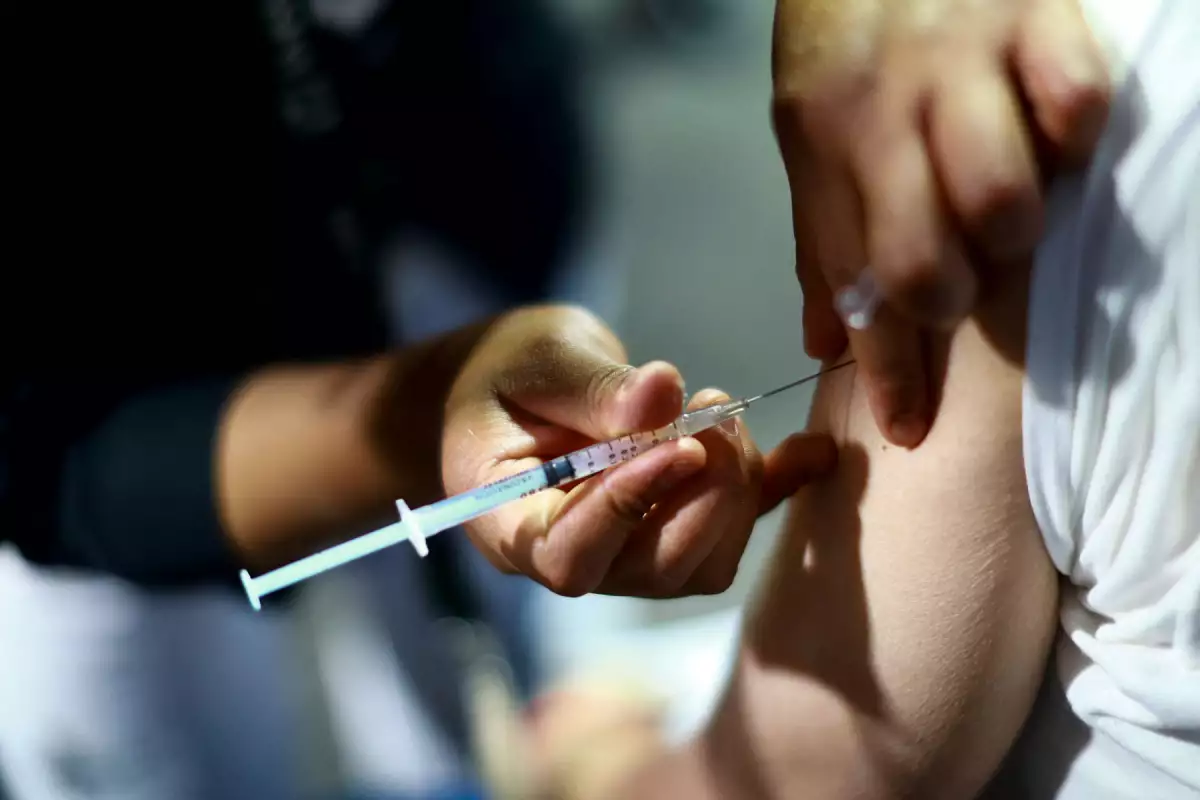 A close-up of a syringe being injected into a person's arm during a vaccination.-$# CAPTION