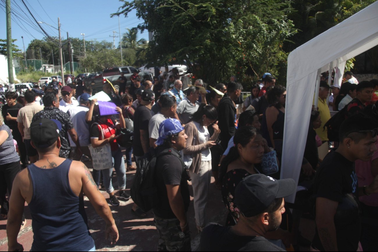 People waiting in long lines under the sun at vehicle registration modules in Cancún