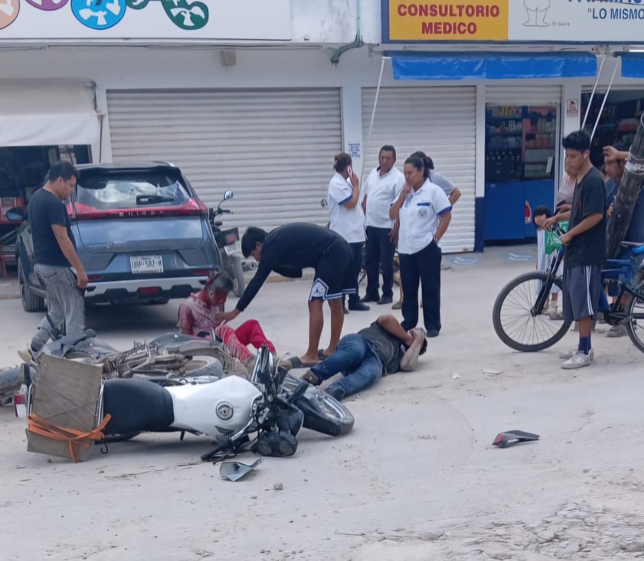 Two motorcyclists lying on the pavement after a collision in Cancún