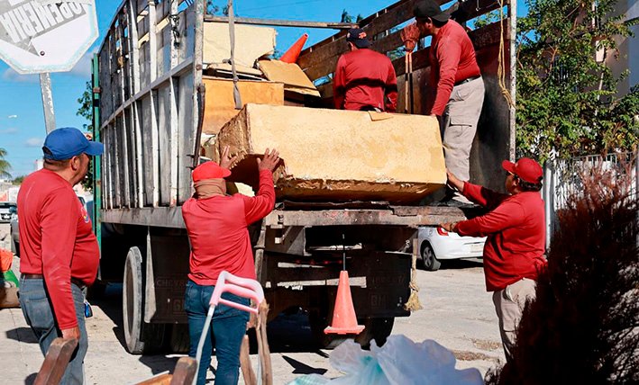 Municipal workers collecting discarded items during a cleanup operation in Cancún