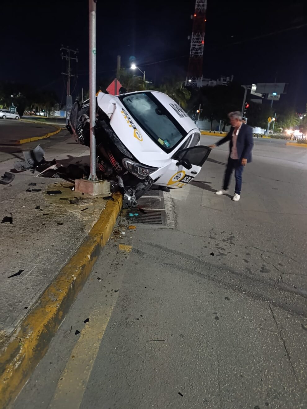 White Nissan Versa federal service vehicle crashed into traffic light pole at Xcaret and Tankah intersection in Cancún